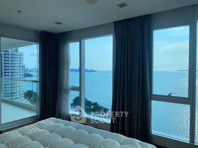 Luxurious bedroom with stunning ocean view and floor-to-ceiling windows in a high-rise apartment.