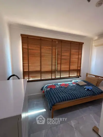 Cozy bedroom with wooden blinds and modern decor, perfect for relaxation and comfort.