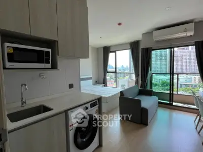 Modern studio apartment with city view, featuring compact kitchen and cozy living area.
