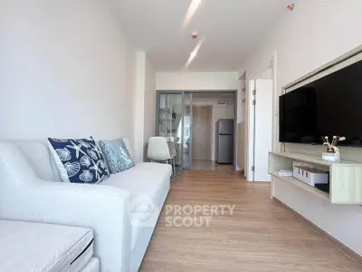 Modern living room with sleek furniture and wall-mounted TV in a bright apartment.