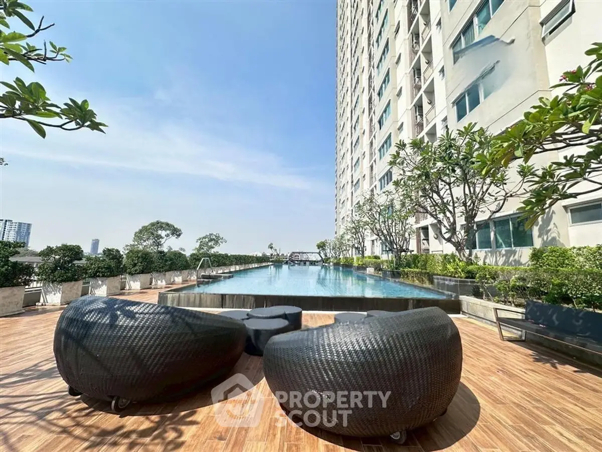 Luxurious high-rise apartment with stunning poolside view and modern outdoor seating.