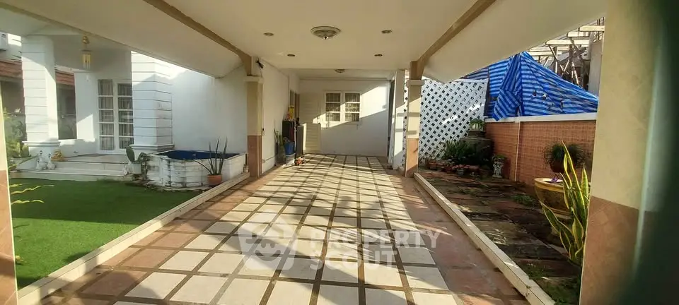 Spacious covered driveway with tiled flooring and garden area in a modern home exterior.