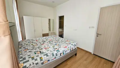 Cozy bedroom with wooden flooring and ample natural light, featuring a comfortable bed and spacious wardrobe.