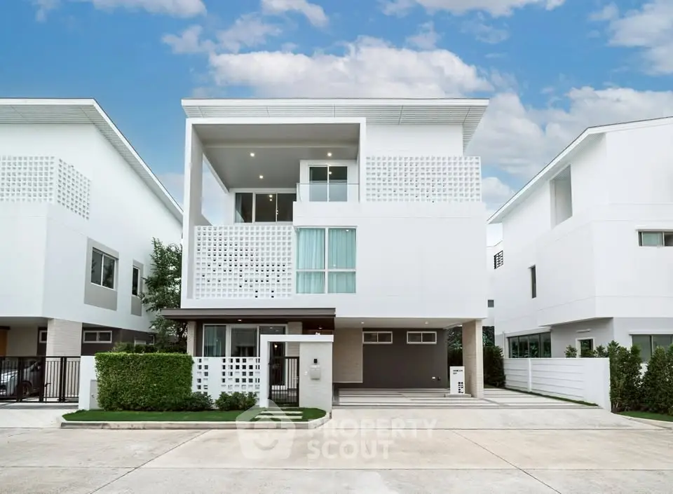 Modern white three-story house with minimalist design and spacious driveway.