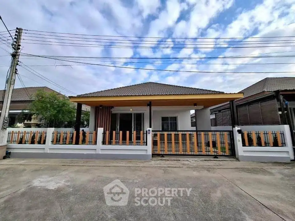 Charming single-story house with modern fence and spacious driveway under a clear blue sky.