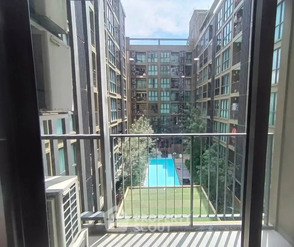 Modern apartment view with pool and garden from balcony, showcasing urban living.