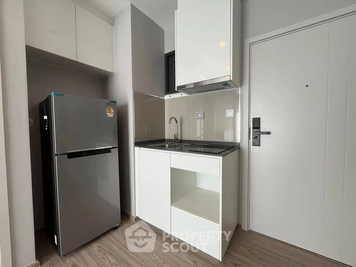 Modern compact kitchen with sleek design and stainless steel fridge
