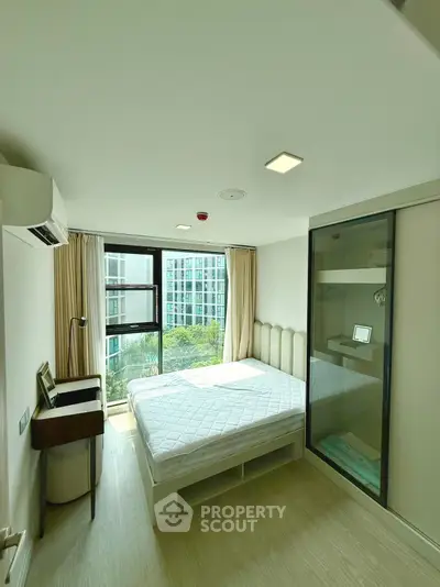 Modern bedroom with large window and city view, featuring a sleek design and ample natural light.
