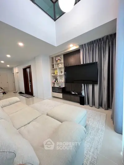 Spacious modern living room with plush sofa and large TV, perfect for relaxation and entertainment.