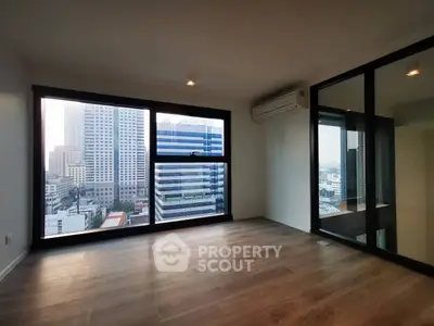 Spacious modern living room with large windows offering stunning city views in a high-rise apartment.