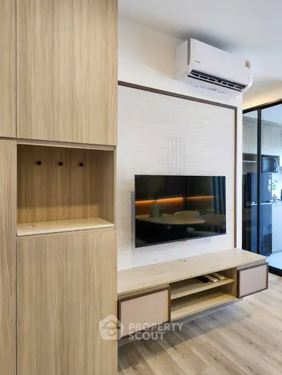 Modern living room with sleek wooden cabinetry and mounted TV, featuring air conditioning for comfort.
