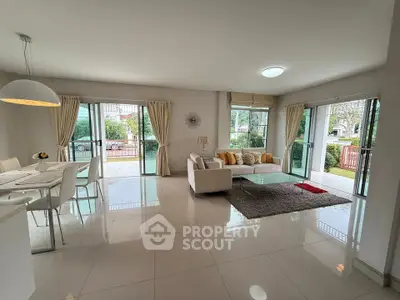 Spacious modern living room with open layout and garden view, featuring elegant decor and abundant natural light.