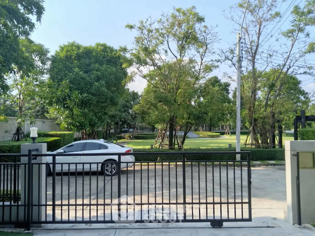 Charming residential entrance with lush greenery and secure gate, perfect for serene living.