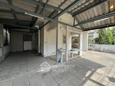 Spacious covered outdoor area with tiled flooring and utility sink, ideal for versatile use.