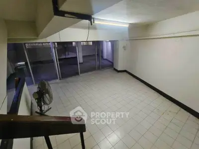 Spacious tiled room with large windows and ceiling light, ideal for versatile use.