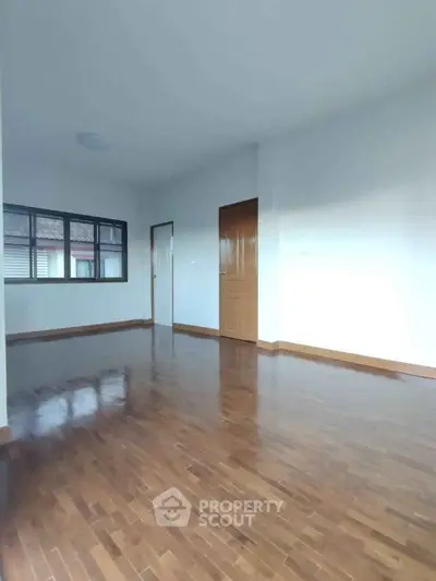 Spacious empty room with polished wooden floors and large window