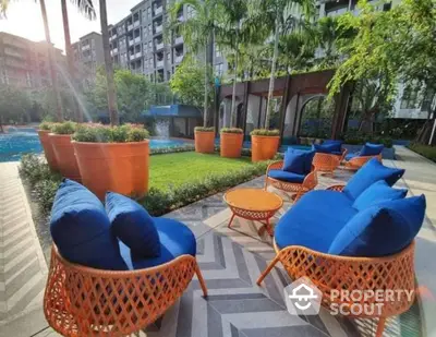 Luxurious outdoor seating area with vibrant blue cushions near a pool in a modern apartment complex.