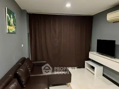 Modern living room with dark leather sofa and wall-mounted TV, featuring sleek design and cozy ambiance.