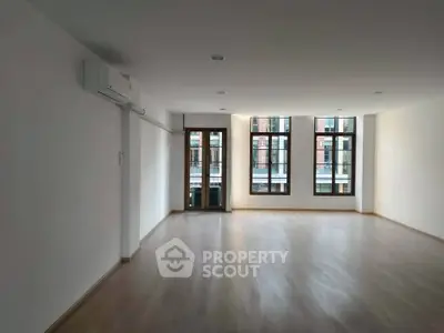 Spacious empty living room with large windows and wooden flooring, perfect for customization.