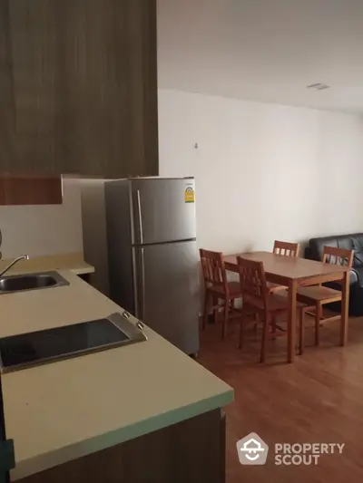 Modern kitchen with dining area and stainless steel fridge in cozy apartment