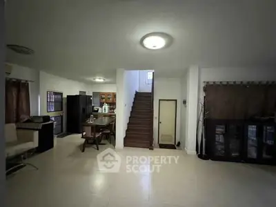 Spacious open-plan living area with modern kitchen and staircase in a stylish home.