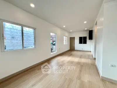 Spacious and bright living room with modern wooden flooring and ample natural light.