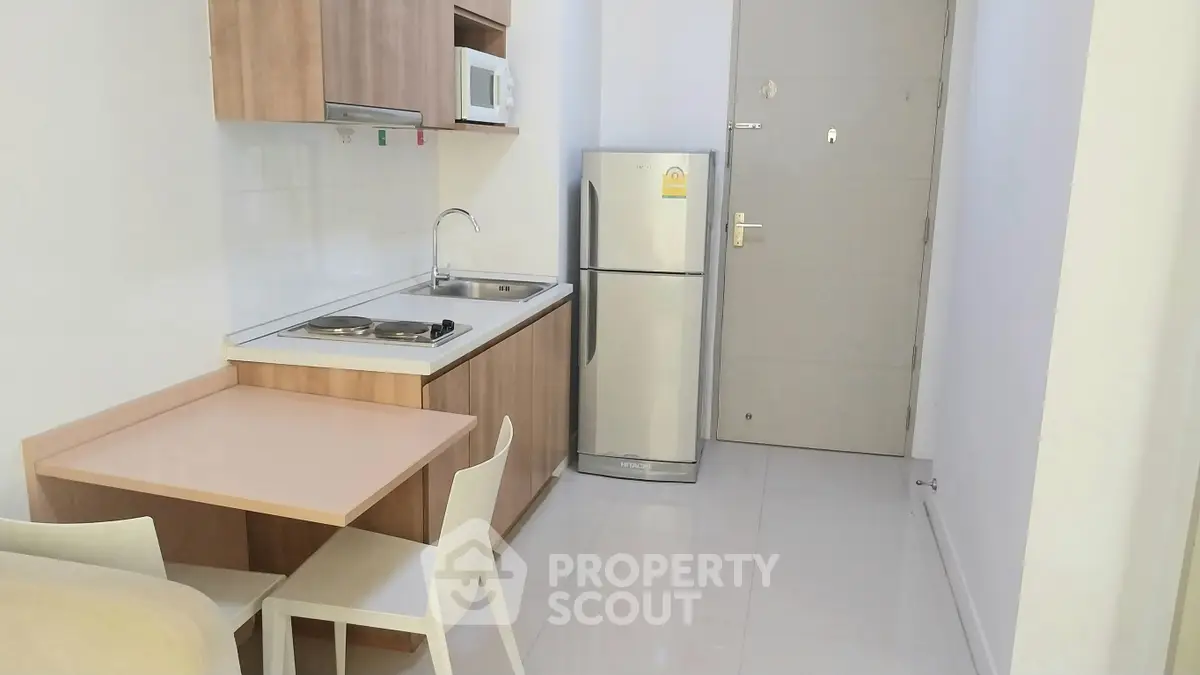 Modern compact kitchen with dining area, featuring sleek cabinetry and stainless steel appliances.