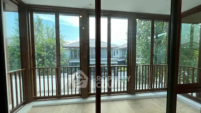 Spacious balcony with wooden railings and large glass doors overlooking residential area.