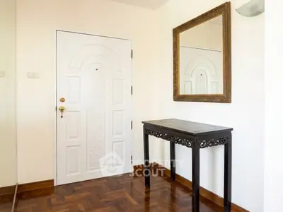 Elegant entryway with ornate mirror and wooden table, showcasing stylish parquet flooring.