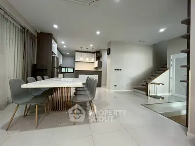 Spacious modern dining area with elegant table and chairs, open kitchen layout, and sleek staircase.