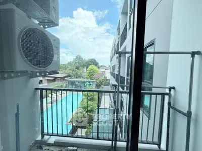 Modern apartment balcony with pool view and lush greenery, perfect for relaxation and leisure.