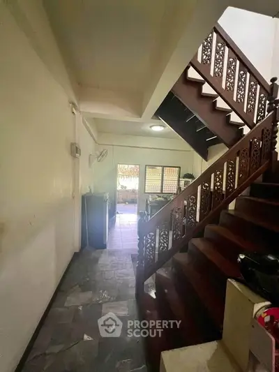 Charming interior with wooden staircase and tiled flooring leading to a cozy kitchen area.