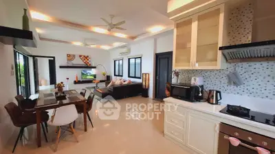 Spacious open-plan living room and kitchen with modern decor and ample natural light.
