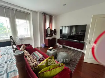 Charming bedroom with elegant decor, featuring a large TV, plush sofa, and ample natural light from large windows.