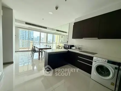 Modern kitchen with sleek cabinets and washing machine, offering a bright city view.