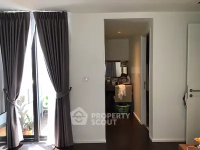 Modern apartment interior with elegant curtains and a glimpse of a cozy balcony.