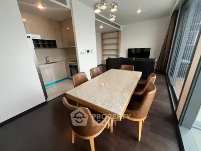 Modern dining area with sleek kitchen and cozy living room in open layout apartment.