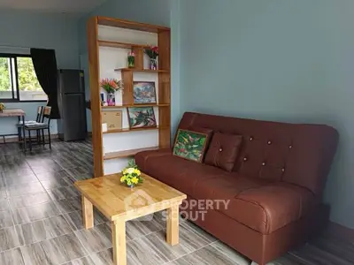 Modern living room with brown leather sofa and wooden coffee table, open layout with kitchen view.