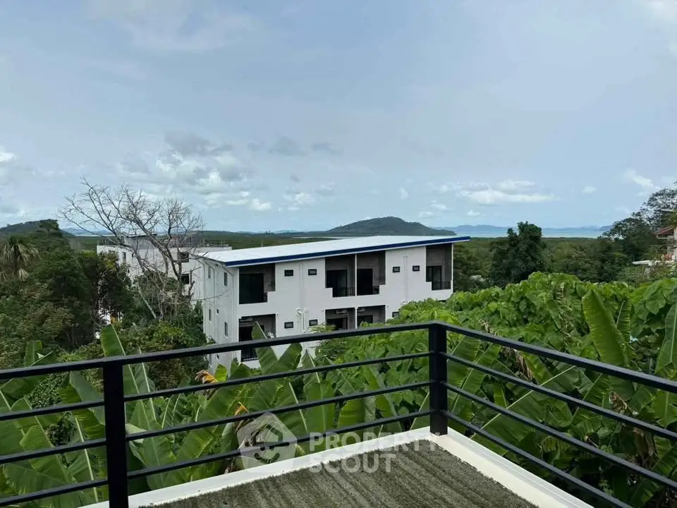 Stunning balcony view overlooking lush greenery and modern building with scenic horizon.