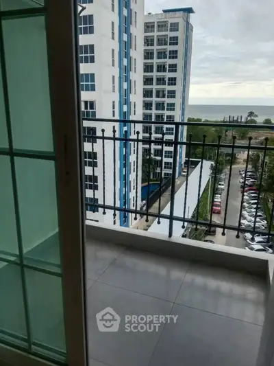 Modern apartment balcony with ocean view and nearby high-rise buildings.