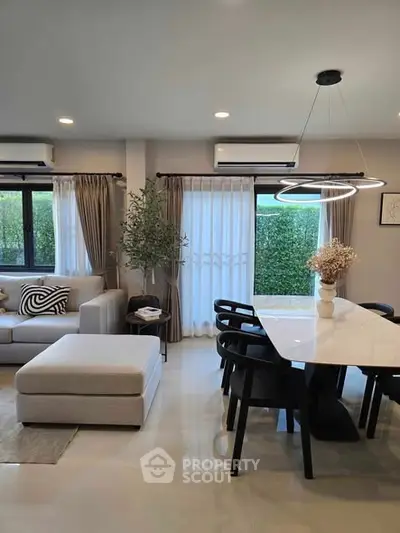 Modern living and dining area with stylish furniture and large windows.