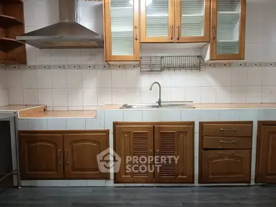 Spacious kitchen with wooden cabinets and modern stainless steel range hood.