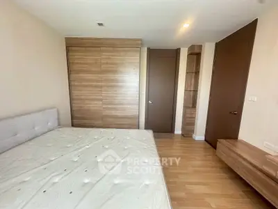 Spacious bedroom with wooden flooring and built-in wardrobe in modern apartment.