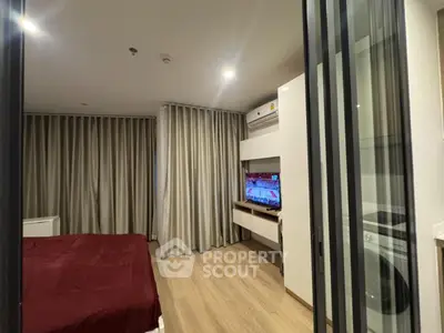 Modern bedroom with sliding glass doors, TV, and washing machine in a stylish apartment.