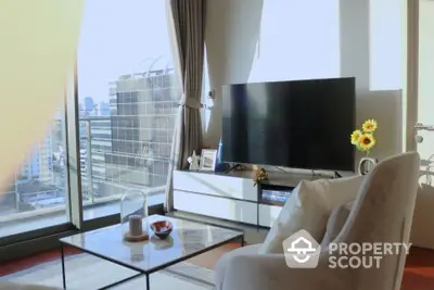 Sunlit modern living room with floor-to-ceiling windows offering a cityscape view, complemented by a cozy seating area and a sleek flat-screen TV.