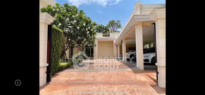 Luxurious villa entrance with spacious driveway and lush greenery