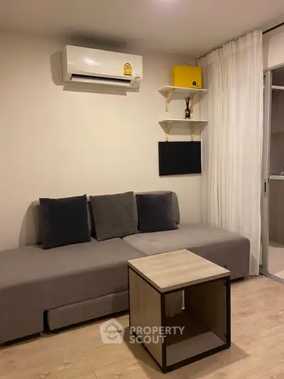Modern living room with sleek sofa, air conditioning, and minimalist decor in a cozy apartment.