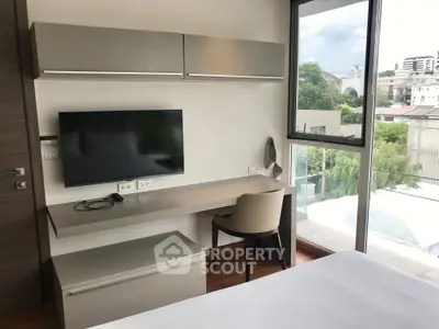 Modern bedroom with sleek desk and city view, perfect for urban living.