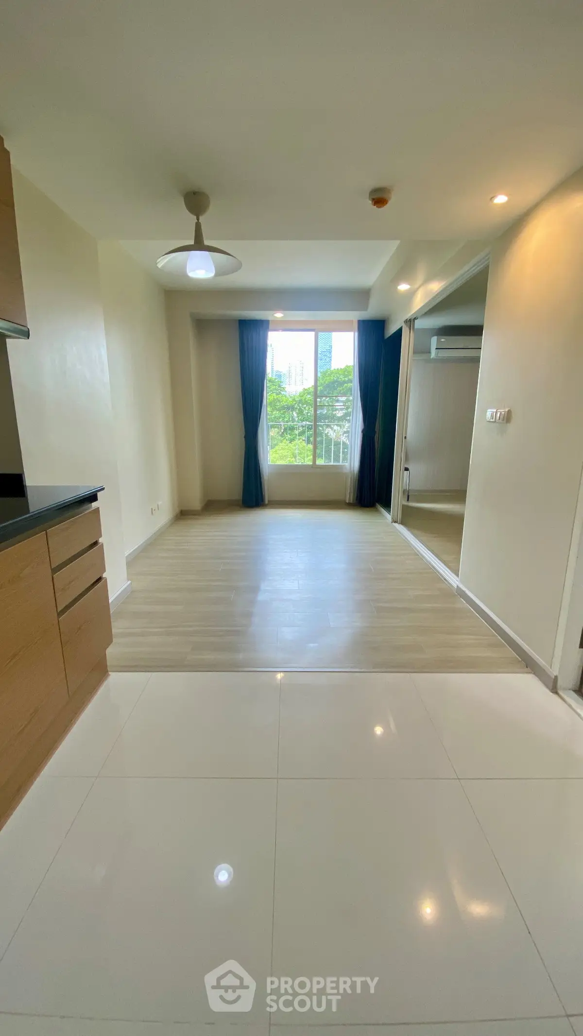 Spacious modern living room with large window and sleek flooring, perfect for urban living.