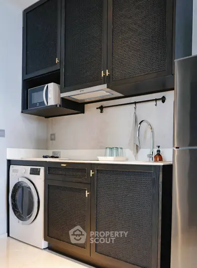 Modern kitchen with sleek black cabinets, built-in microwave, and washing machine